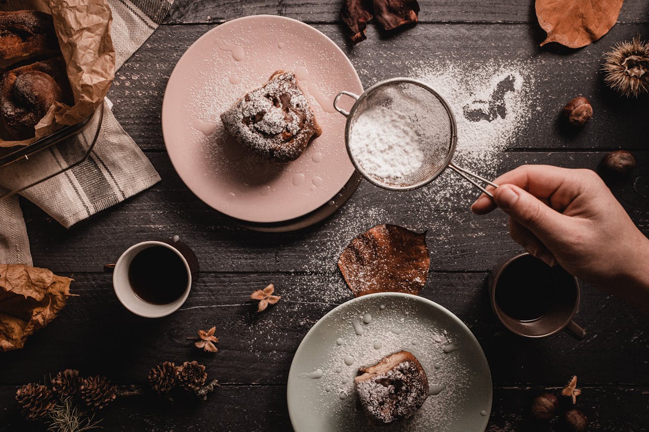 Flat lay of cinnamon rolls with coffee, dusted with powdered sugar on rustic wooden table.