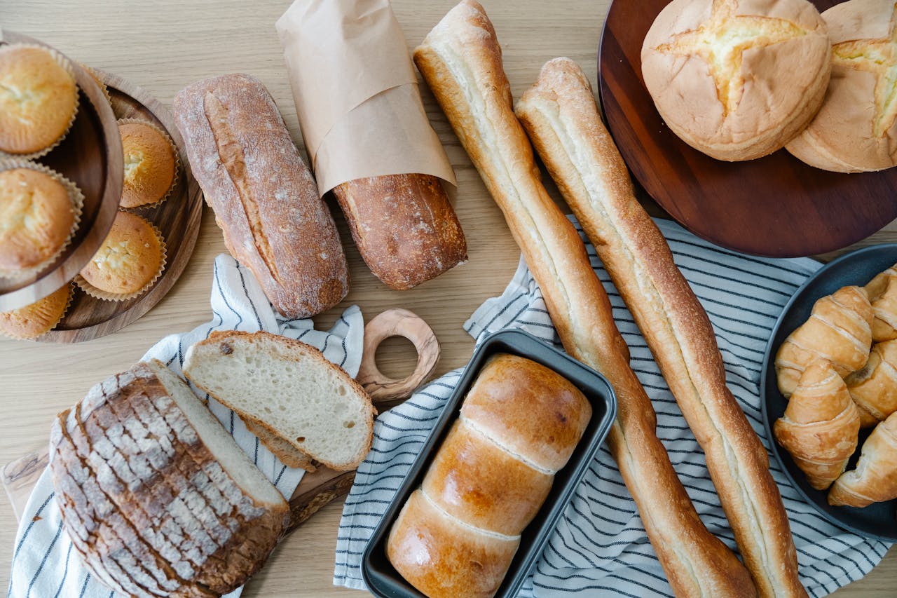 Top view of freshly baked bread and pastries on a wooden table, perfect for breakfast and culinary photography.